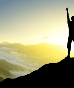 A person standing on top of a mountain with the sun setting.