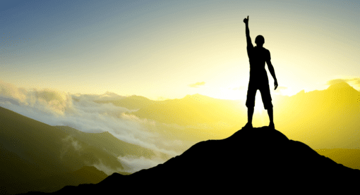 A person standing on top of a mountain with the sun setting.