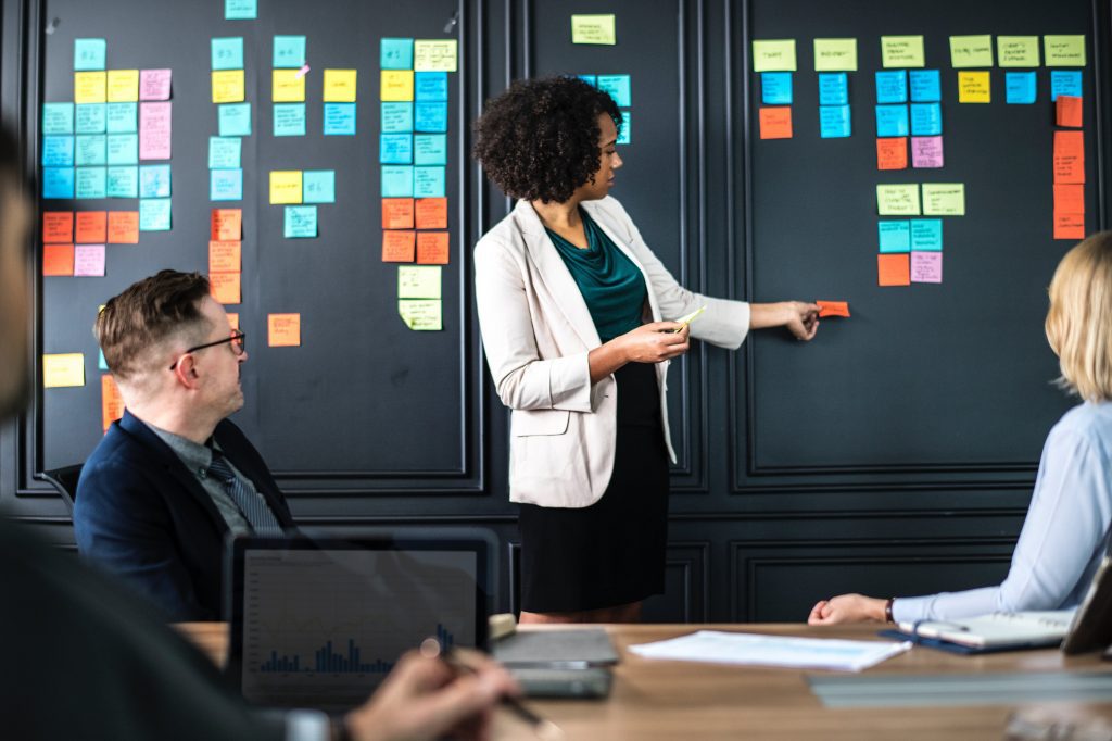 A woman standing in front of a board with sticky notes on it.