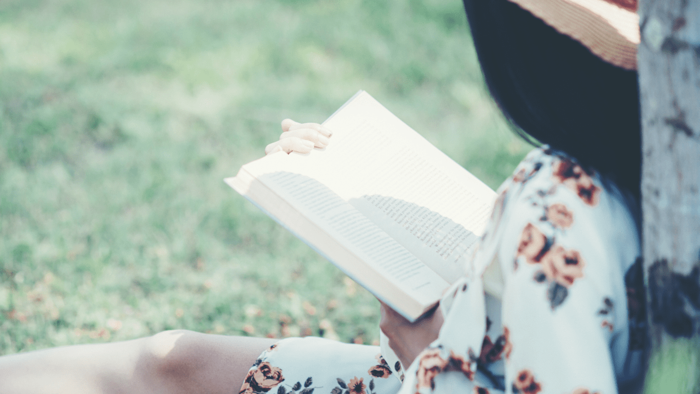 A person sitting in the grass reading a book.