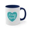 A blue and white coffee mug with the words " loving myself ".